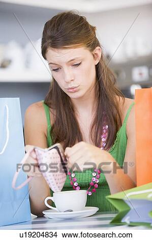 Young woman sitting at a table checking change purse View Large Photo Image Picture - Young woman sitting at a table checking change purse. Fotosearch