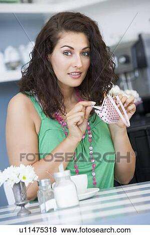 Stock Photo - Young woman sitting at a table checking change purse. Fotosearch