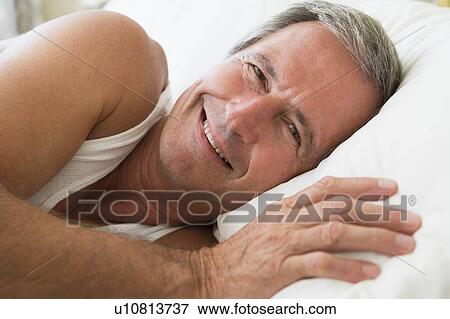 Man lying in bed smiling View Large Photo Image Stock Photo - Man lying in bed smiling. Fotosearch