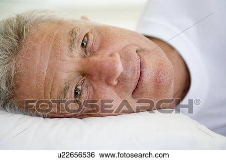 Stock Photograph - Man lying in bed. Fotosearch