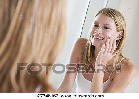 Woman in bathroom applying face cream smiling View Large Photo Image Stock Image - Woman in bathroom applying face cream smiling. Fotosearch