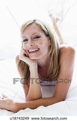 Woman lying in bed laughing View Large Photo Image Stock Photo - Woman lying in bed laughing. Fotosearch