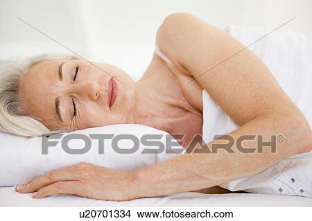 Picture - Woman lying in bed sleeping. Fotosearch