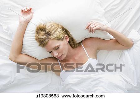 Stock Image - Woman lying in bed sleeping. Fotosearch