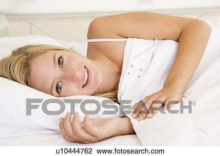 Woman lying in bed smiling View Large Photo Image Stock Image - Woman lying in bed smiling. Fotosearch