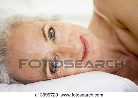 Stock Image - Woman lying in bed smiling. Fotosearch