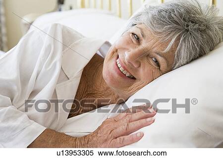 Stock Photography - Woman lying in bed smiling. Fotosearch