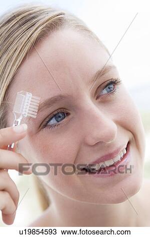 Stock Image - Woman with eyebrow brush smiling. Fotosearch