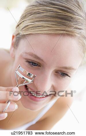Stock Image - Woman with eyelash curler smiling. Fotosearch
