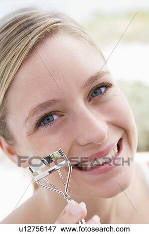 Woman with eyelash curler smiling View Large Photo Image Stock Photo - Woman with eyelash curler smiling. Fotosearch