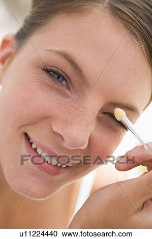Stock Image - Woman with eyeshadow applicator smiling. Fotosearch