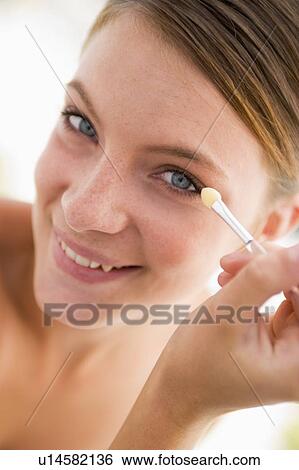 Stock Photograph - Woman with eyeshadow applicator smiling. Fotosearch