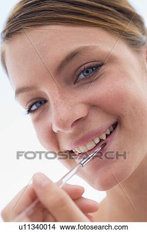 Woman with lipgloss applicator smiling View Large Photo Image Picture - Woman with lipgloss applicator smiling. Fotosearch