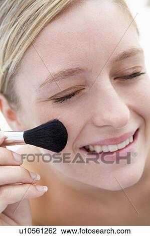 Stock Image - Woman with makeup brush smiling. Fotosearch