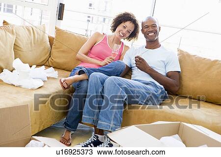 Couple relaxing with champagne by boxes in new home smiling View Large Photo Image Stock Image - Couple relaxing with champagne by boxes in new home smiling. Fotosearch