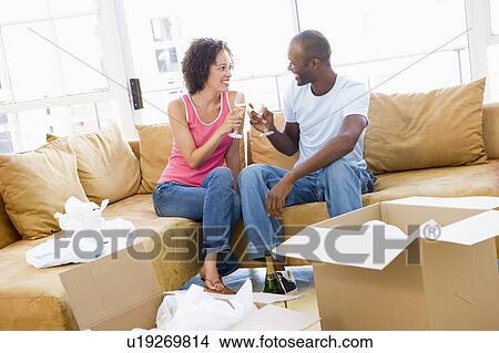 Couple toasting champagne by boxes in new home smiling View Large Photo Image Picture - Couple toasting champagne by boxes in new home smiling. Fotosearch