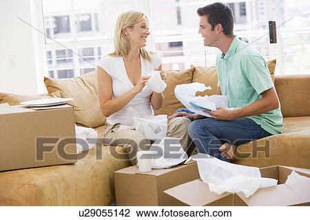 Stock Image - Couple unpacking boxes in new home smiling. Fotosearch