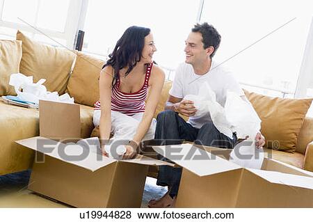 Couple unpacking boxes in new home smiling View Large Photo Image Stock Photo - Couple unpacking boxes in new home smiling. Fotosearch
