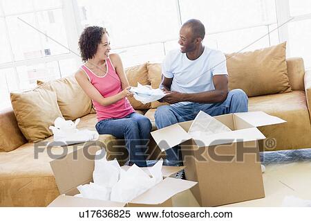 Couple unpacking boxes in new home smiling View Large Photo Image Stock Photography - Couple unpacking boxes in new home smiling. Fotosearch