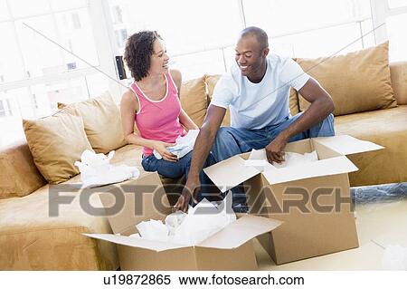 Stock Photography - Couple unpacking boxes in new home smiling. Fotosearch