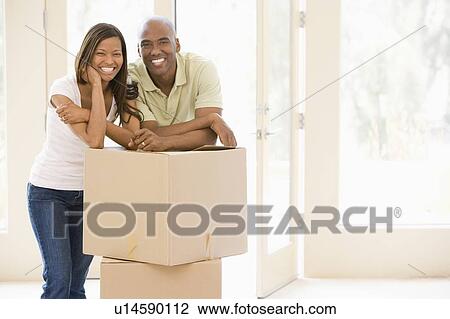 Couple with boxes in new home smiling View Large Photo Image Stock Image - Couple with boxes in new home smiling. Fotosearch
