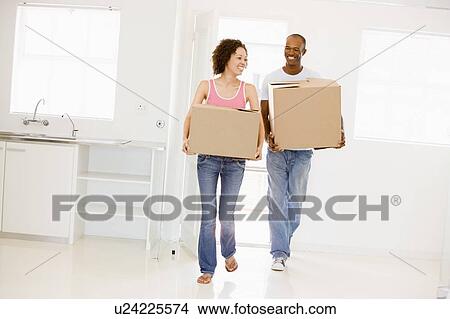 Couple with boxes moving into new home smiling View Large Photo Image Picture - Couple with boxes moving into new home smiling. Fotosearch