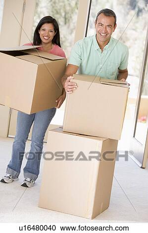Stock Image - Couple with boxes moving into new home smiling. Fotosearch