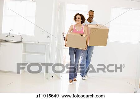 Couple with boxes moving into new home smiling View Large Photo Image Stock Photo - Couple with boxes moving into new home smiling. Fotosearch