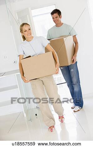 Couple with boxes moving into new home smiling View Large Photo Image Stock Photo - Couple with boxes moving into new home smiling. Fotosearch