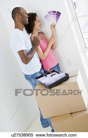Couple with paint swatches in new home smiling View Large Photo Image Stock Photography - Couple with paint swatches in new home smiling. Fotosearch