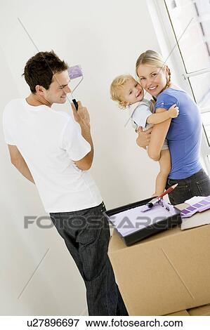 Stock Photo - Family painting room in new home smiling. Fotosearch