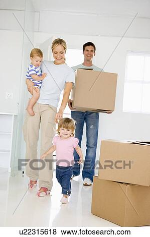 Stock Photo - Family with box moving into new home smiling. Fotosearch