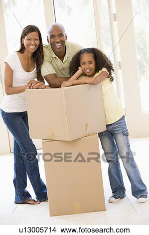 Picture - Family with boxes in new home smiling. Fotosearch