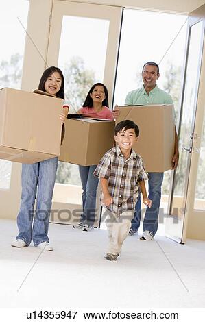 Stock Photo - Family with boxes moving into new home smiling. Fotosearch