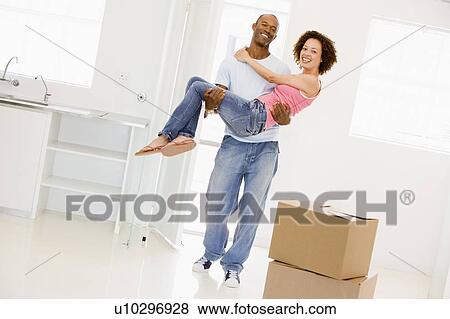 Husband holding wife in new home smiling View Large Photo Image Stock Photo - Husband holding wife in new home smiling. Fotosearch