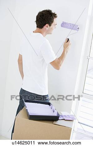 Stock Image - Man painting room in new home smiling. Fotosearch