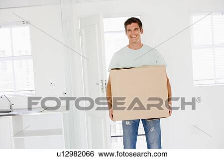 Man with box moving into new home smiling View Large Photo Image Stock Photograph - Man with box moving into new home smiling. Fotosearch