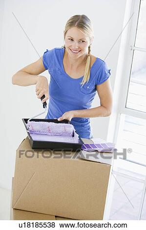 Woman painting room in new home smiling View Large Photo Image Stock Photo - Woman painting room in new home smiling. Fotosearch