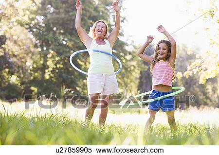 Grandmother and granddaughter at a park hula hooping and smiling View Large Photo Image Stock Photography - Grandmother and granddaughter at a park hula hooping and smiling. Fotosearch