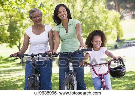 Stock Photograph - Grandmother with adult daughter and grandchild riding bikes. Fotosearch