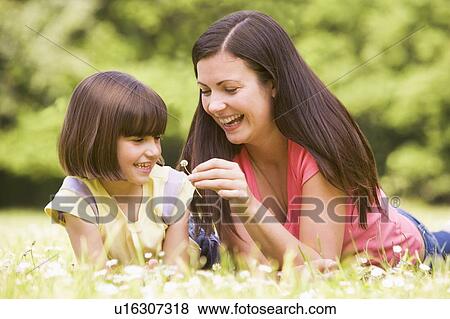 Stock Photo - Mother and daughter lying outdoors with flower smiling. Fotosearch