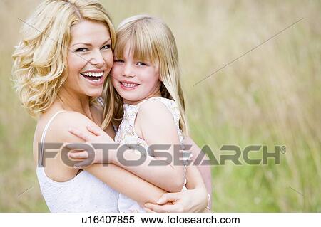 Stock Photography - Mother holding daughter outdoors smiling. Fotosearch