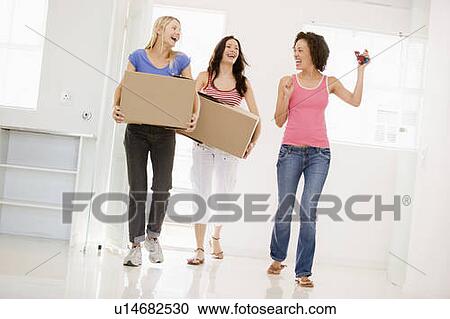 Stock Image - Three girl friends moving into new home smiling. Fotosearch