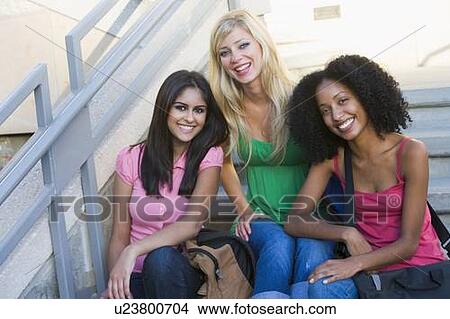 Picture - Three women sitting on staircase outdoors smiling (high key). Fotosearch