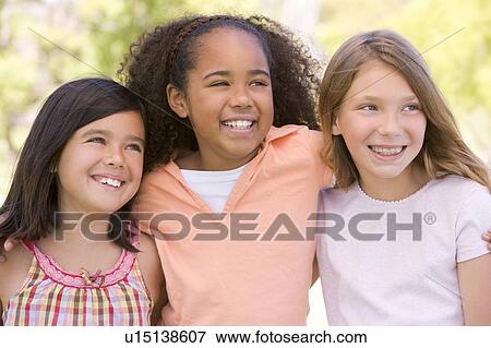 Three young girl friends outdoors smiling View Large Photo Image Stock Photo - Three young girl friends outdoors smiling. Fotosearch