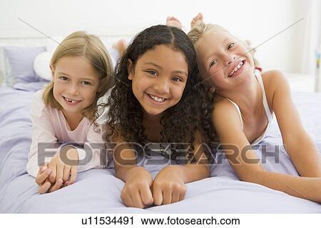 Three Young Girls Lying On A Bed In Their Pajamas View Large Photo Image Stock Image - Three Young Girls Lying On A Bed In Their Pajamas. Fotosearch