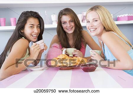 Three young woman sitting at a table having tea and a snack View Large Photo Image Stock Image - Three young woman sitting at a table having tea and a snack. Fotosearch