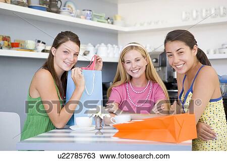 Three young woman sitting at a table taking a break from shopping View Large Photo Image Stock Image - Three young woman sitting at a table taking a break from shopping. Fotosearch