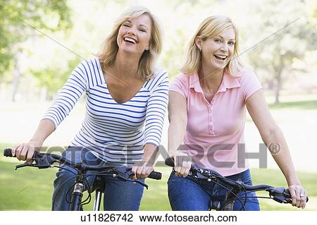 Two friends on bikes outdoors smiling View Large Photo Image Stock Image - Two friends on bikes outdoors smiling. Fotosearch