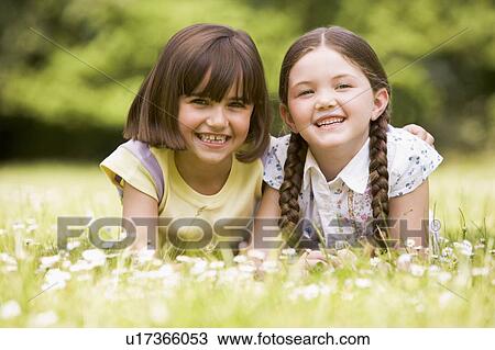 Stock Image - Two sisters lying outdoors smiling. Fotosearch